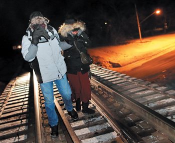 Refugees walk along railway tracks from the United States to enter Canada at Emerson, Man.<br /> in February. Photo: Reuters / Lyle Stafford